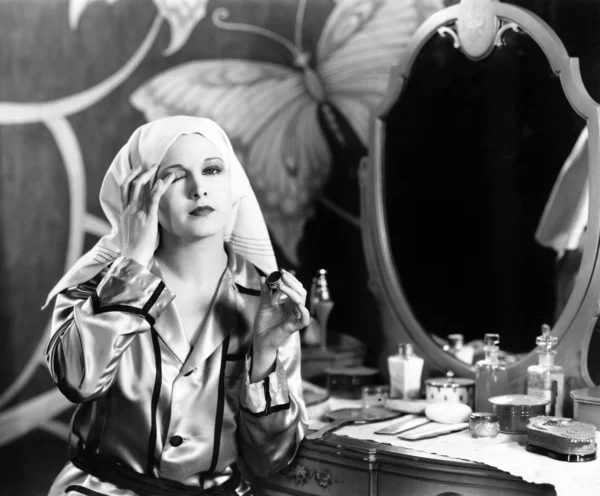 Женщина сидит перед своим тщеславием и снимает ее макияж — стоковое фото