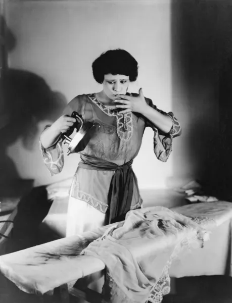 Женщина с пальцем во рту после того, как обожглась утюгом — стоковое фото