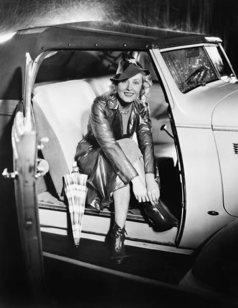 Mulher sentada em um carro colocando em seus sapatos — Fotografia de Stock