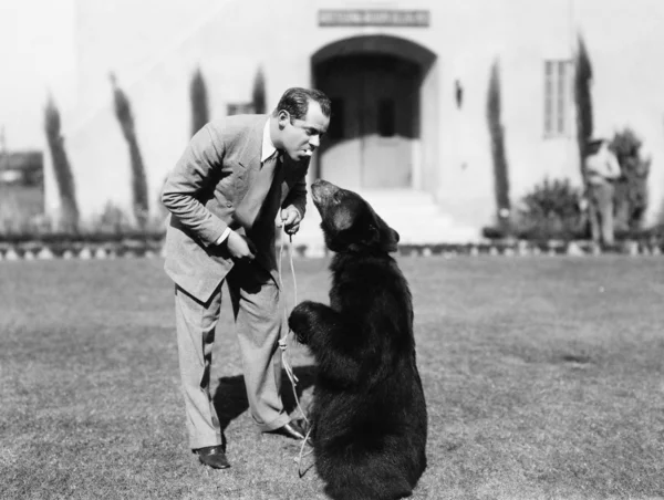 Un homme nourrit un ours debout sur sa pelouse — Photo