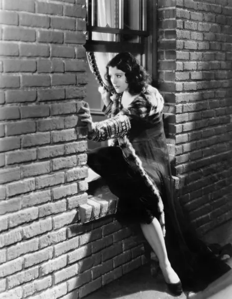 Femme essayant de s'échapper par une fenêtre — Photo