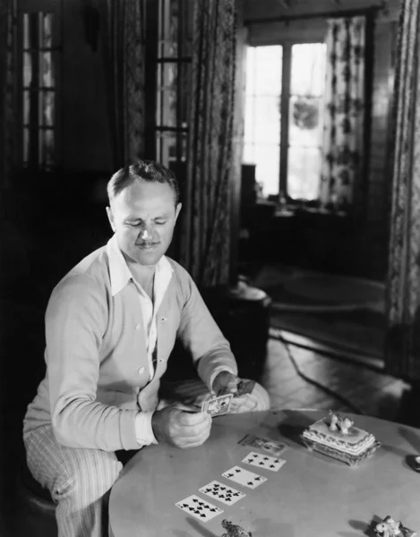 Człowiek siedzi w jego pokój dzienny kart do gry — Zdjęcie stockowe