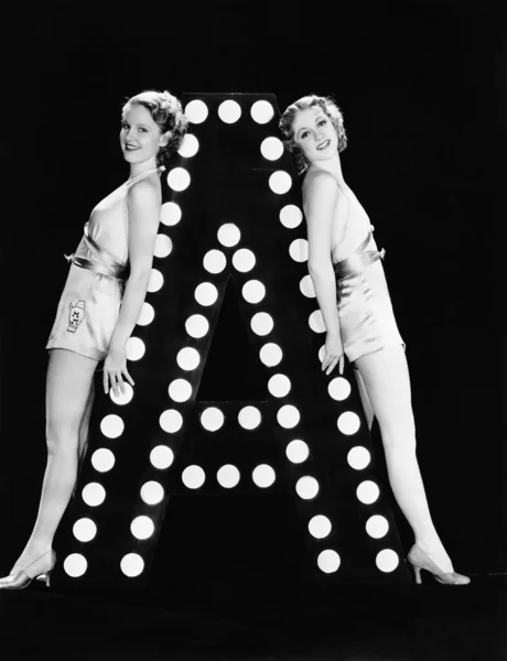 Zwei junge Frauen posieren mit dem Buchstaben a — Stockfoto