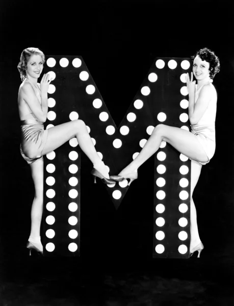 Två unga kvinnor poserar med bokstaven m — Stockfoto