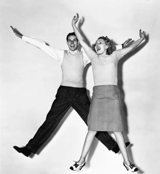 Casal pulando com os braços estendidos — Fotografia de Stock