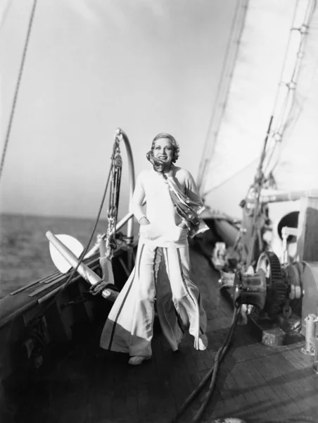 Jovem mulher de pé em um convés de um veleiro e sorrindo — Fotografia de Stock