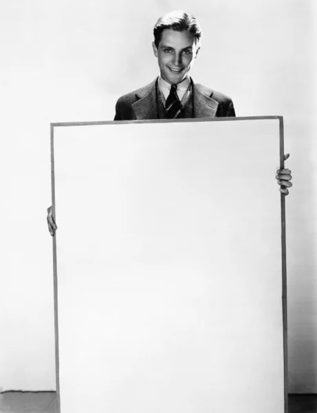 Portret van een zakenman holding een poster en glimlachen — Stockfoto