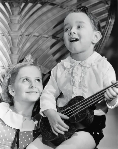 Närbild av en pojke som spelar en gitarr med sin syster — Stockfoto