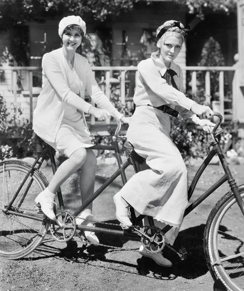 Portrait of two young women sitting on a tandem bicycle — Stock Photo, Image