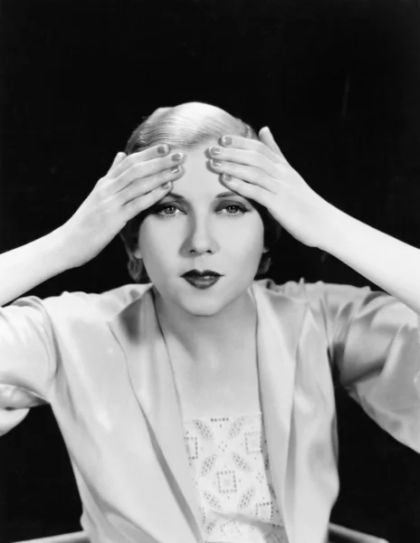 Porträt einer jungen Frau, die sich beide Hände auf die Stirn legt — Stockfoto