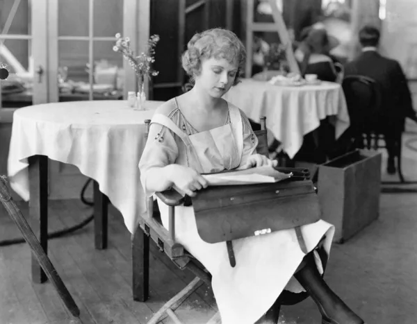 Genç kadın bir sandalyede oturuyor ve belgeleri okuma — Stok fotoğraf