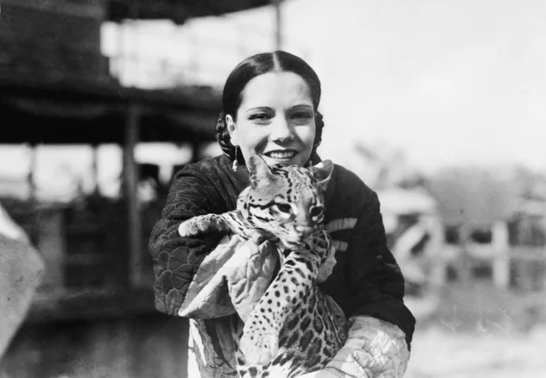 Porträt einer jungen Frau, die ein Gepardenjunges trägt und lächelt — Stockfoto