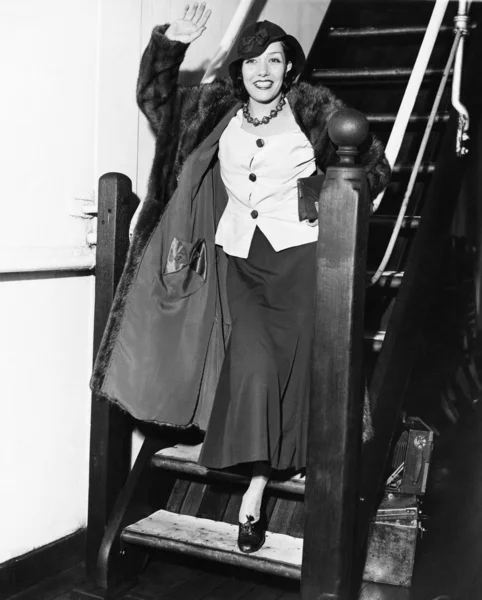 Mujer joven saludando en una escalera y sonriendo — Foto de Stock