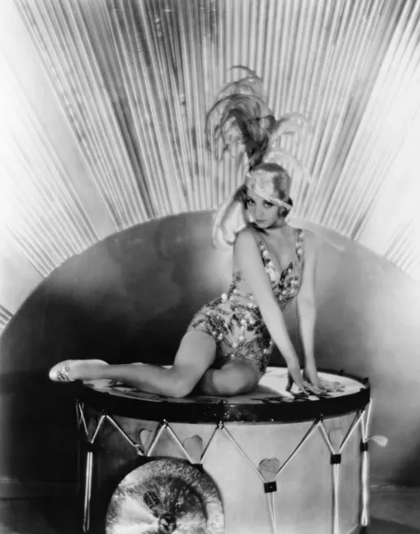 Retrato de una joven sentada sobre un tambor con un sombrero de plumas — Foto de Stock