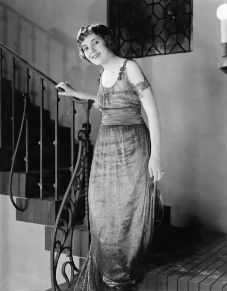 Νεαρή γυναίκα κινείται κάτω από μια σκάλα και χαμογελαστός — Φωτογραφία Αρχείου