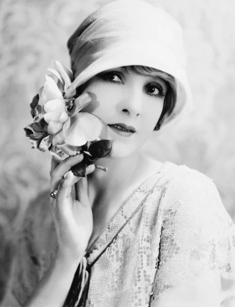 Portrét mladé ženy s kloboukem drží květiny — Stock fotografie