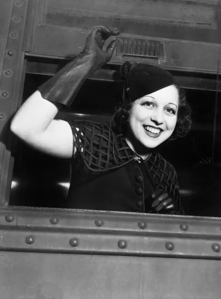 Niski kąt widzenia młoda kobieta, patrząc przez okno pociągu i uśmiechając się — Zdjęcie stockowe