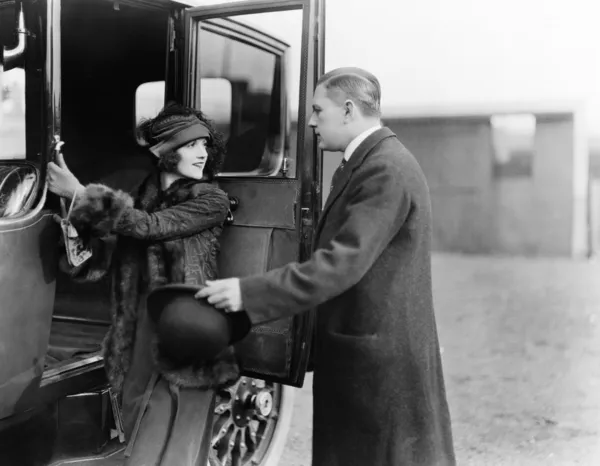 Perfil de um homem ajudando uma jovem a embarcar em um carro — Fotografia de Stock
