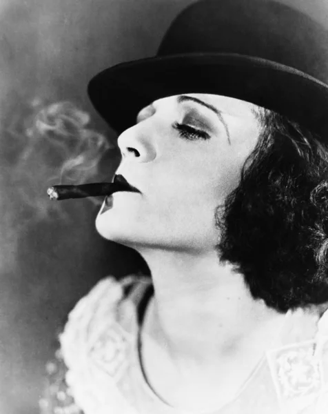 Portret van een jonge vrouw met een hoed dat roken een sigaar — Stockfoto
