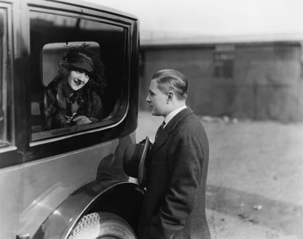 Молодая женщина смотрит на мужчину через окно машины — стоковое фото