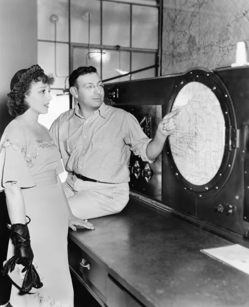 Homem explicando sobre radar para uma jovem mulher em uma sala de controle — Fotografia de Stock