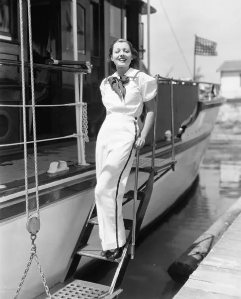 Retrato de una mujer joven de pie en las escaleras de un barco y sonriendo —  Fotos de Stock
