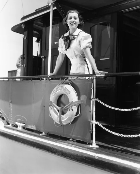 Mladá žena stojící na zábradlí lodi a s úsměvem — Stock fotografie