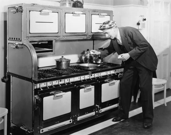 Człowiek łamanie jajko na patelni w kuchni — Zdjęcie stockowe