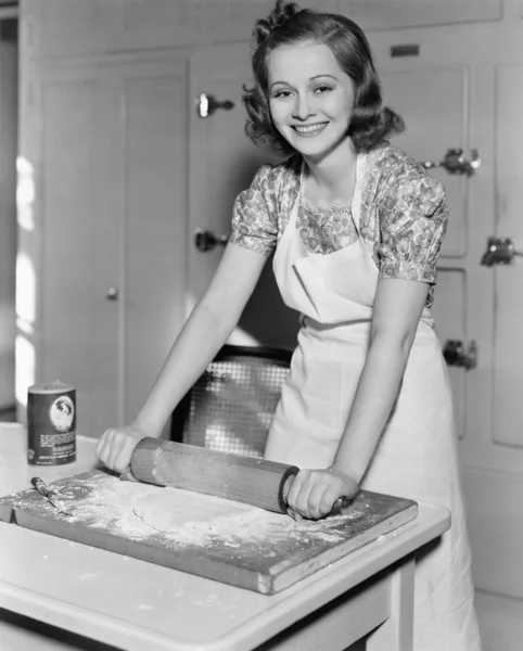 Молодая женщина катит тесто на кухне — стоковое фото