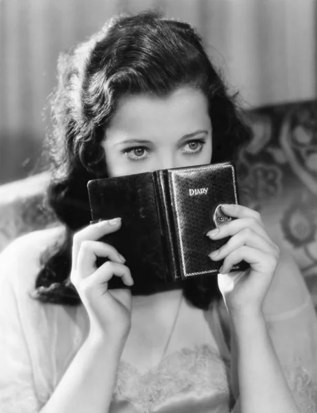 Portrait d'une jeune femme tenant un journal intime et réfléchissant — Photo