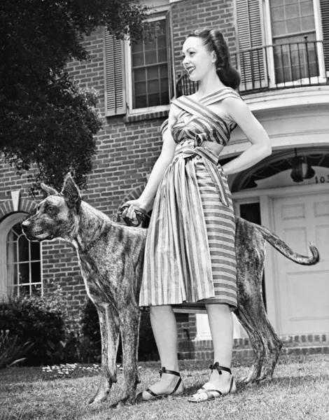 Junge Frau steht mit ihrem großen Dogen in einem Hof — Stockfoto