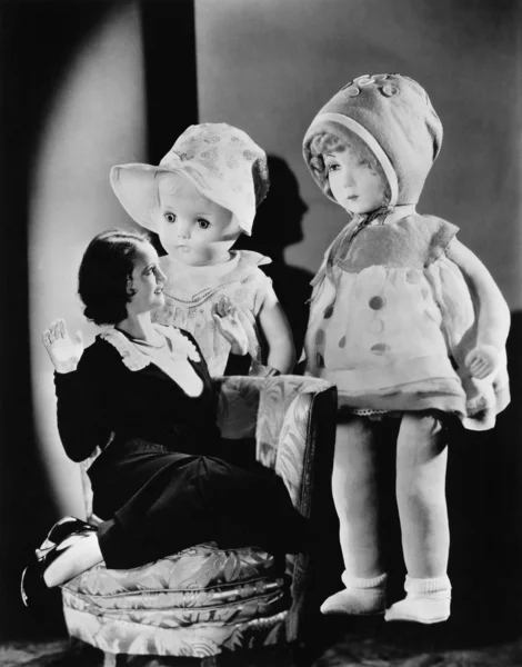Kobieta siedzi na krześle i patrząc na dwa duże lalki — Zdjęcie stockowe
