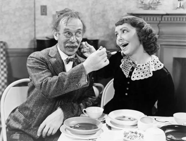 Portrait d'une femme et d'un homme se nourrissant mutuellement de soupe à table — Photo