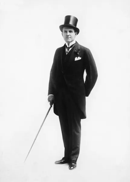 Retrato de un hombre con sombrero de copa y traje de la mañana sosteniendo un bastón —  Fotos de Stock