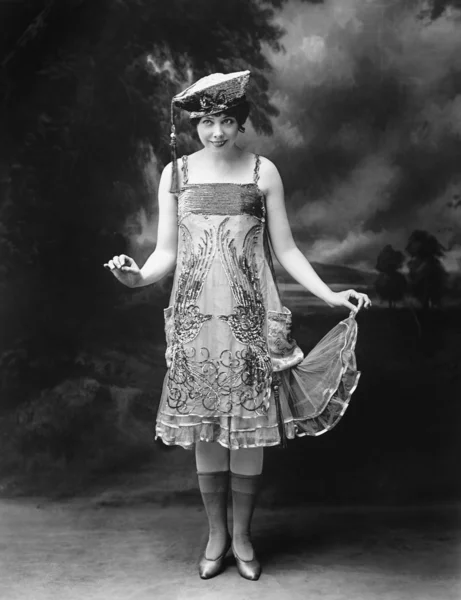 Kvinnan bär en hatt och utsmyckade klänning och ler — Stockfoto