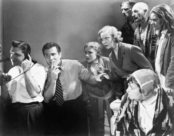 Man talking on the telephone and his friends looking at him and trying to listen