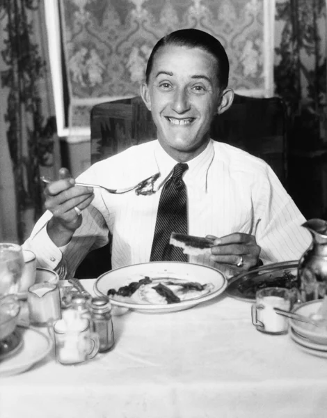 Νεαρός άνδρας, έχοντας πρωινό και χαμογελαστός — Φωτογραφία Αρχείου