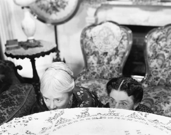 Twee vrouwen verbergen achter een tafel en kijkt uit over de rand — Stockfoto