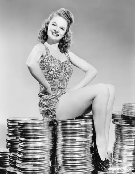 Portrait of a young woman sitting on stacks of film canisters — Stock Photo, Image