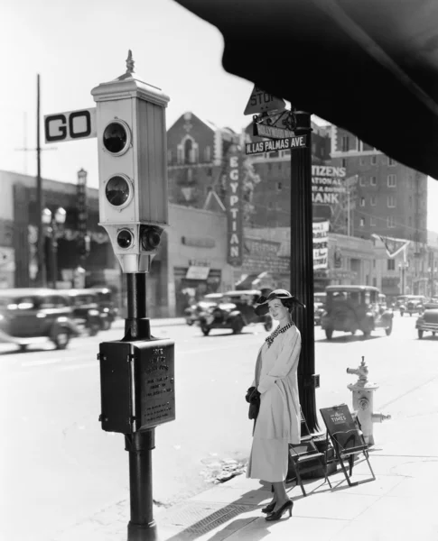 Perfil de uma jovem mulher de pé perto de uma luz de parada — Fotografia de Stock