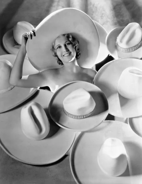 Portrait of a young woman covered with hats — Stock Photo, Image