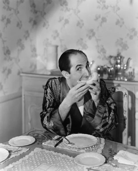 Retrato de um homem maduro sentado na mesa de jantar e comendo frutas — Fotografia de Stock