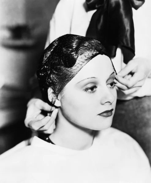 Cabeleireiro amarrando rede de cabelo no cabelo de uma jovem — Fotografia de Stock