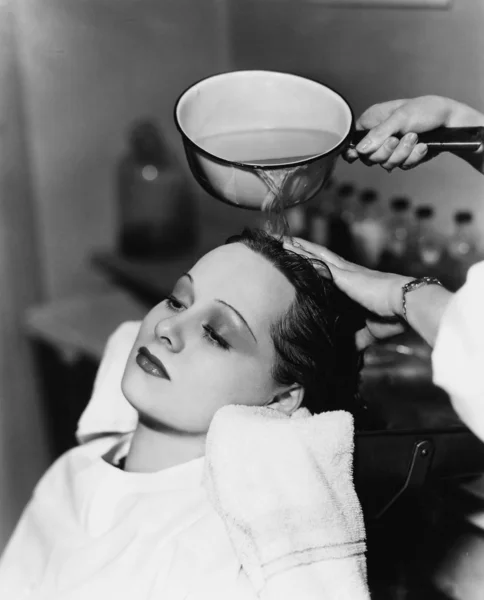 Cabeleireiro limpeza cabelo de uma jovem mulher em um salão de cabeleireiro — Fotografia de Stock