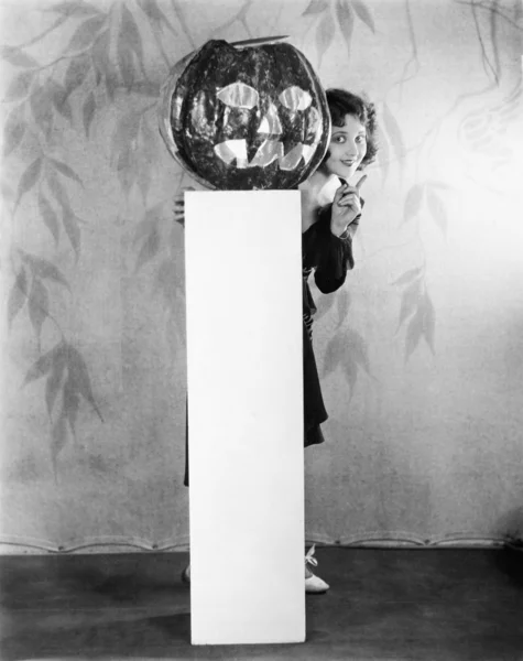 Mladá žena pokukování z pozadí Jack o ' Lantern — Stock fotografie