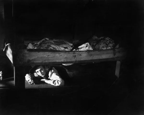 Mujer joven escondida debajo de la cama — Foto de Stock