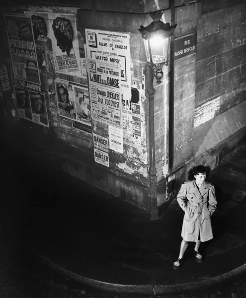 High angle view of a young woman waiting next to a lantern on a dark street corner — Stock Photo, Image