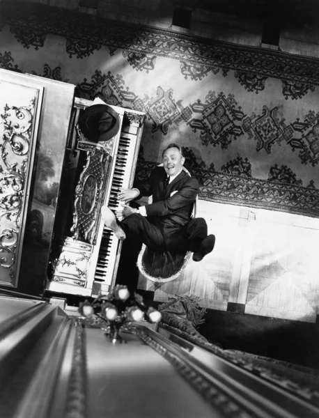 Hoge hoekmening van een man die achterover leunen op een stoel en een piano spelen — Stockfoto