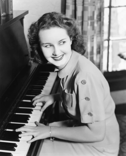Perfil de uma jovem tocando piano e sorrindo — Fotografia de Stock