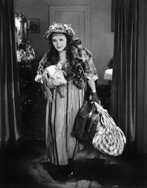 Bir bavul ve bir domuz taşıyan genç bir kadın — Stok fotoğraf